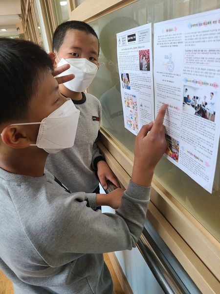 아이들이 복도에 부착된 장애인식개선 신문을 들여다 보고 있다.