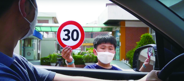 이원초 학생들이 학교 앞을 지나는 운전자를 향해 학교 앞 시속 30km 표지판을 들어 보이고 있다.