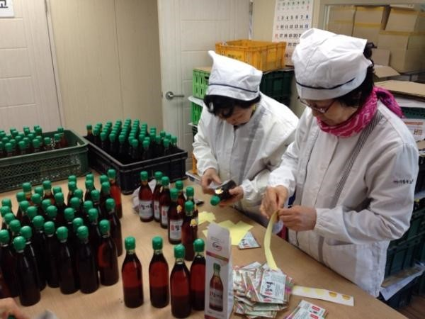 노인일자리 사업에 참여한 어르신들이 한 가공공장에서 병에 담긴 제품을 확인하고 있다.